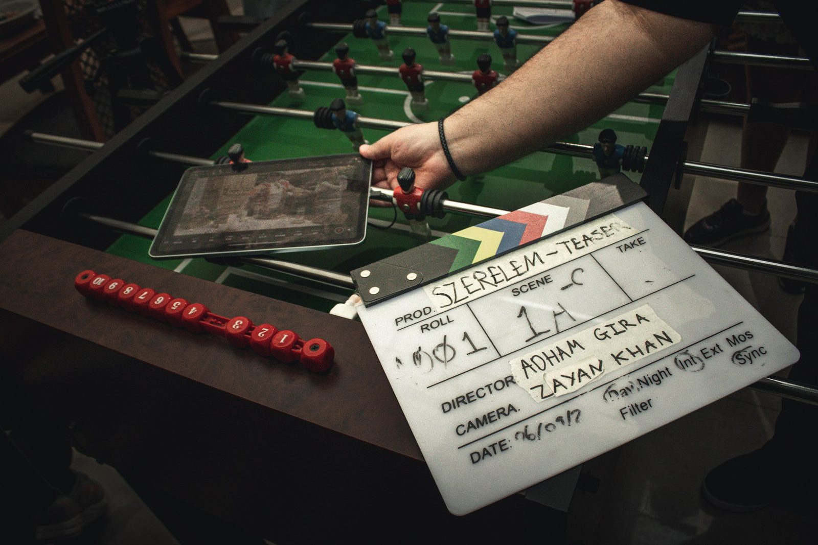 Clapperboard resting on a foosball table between setups
