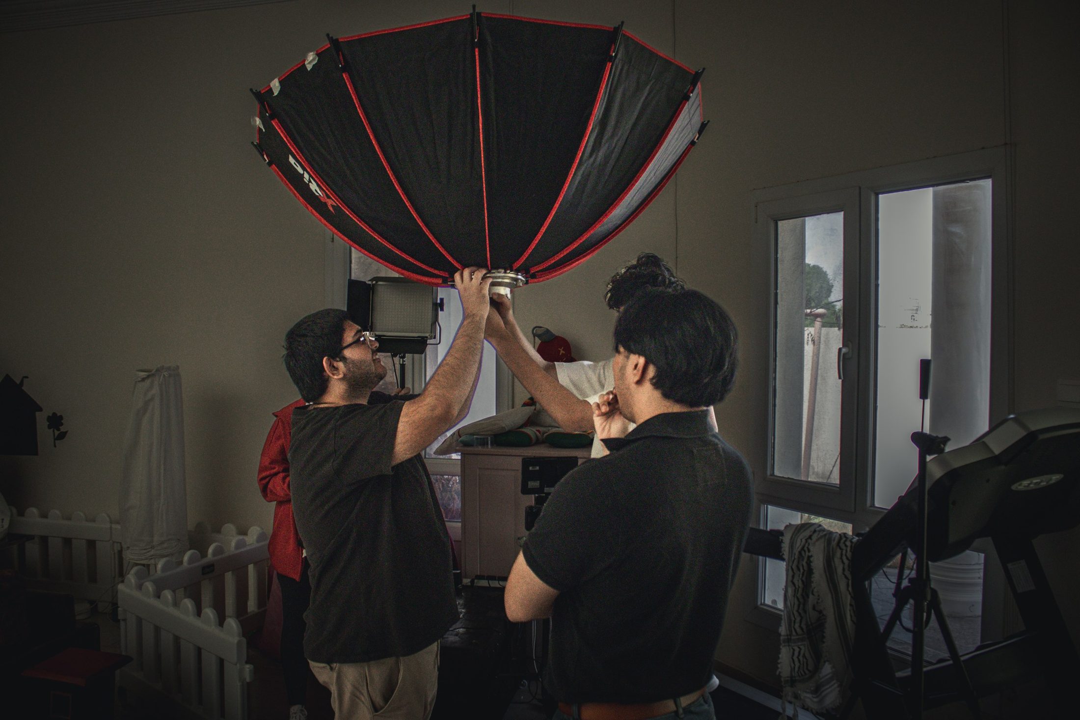 Crew raise a large umbrella light into position on set